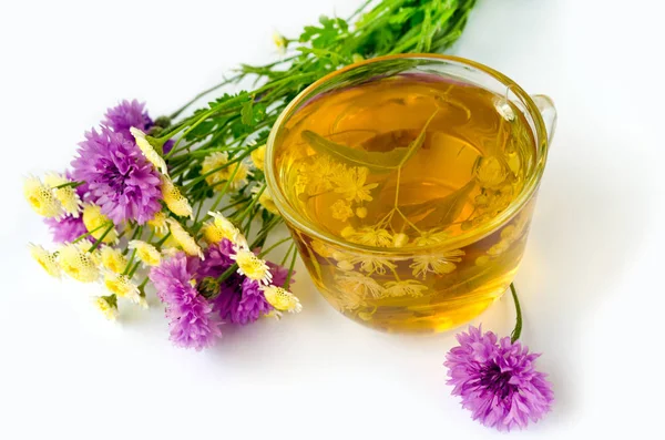 Kireç çay şeffaf bir fincan beyaz bir arka plan ve kır çiçekleri buketi