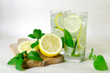 Limon nane Detoks su. Ev yapımı limonata nane, limon ve buz içinde hafif bir arka plan üzerinde gözlük. Ahşap masa, dilimlenmiş limon ve nane yaprakları