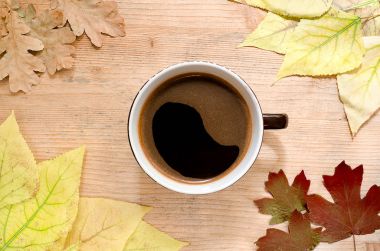 Sonbahar natürmort - büyük bir fincan kahve sonbahar renkli tarafından çevrili bir ahşap masa üzerinde bırakır. Üstten Görünüm