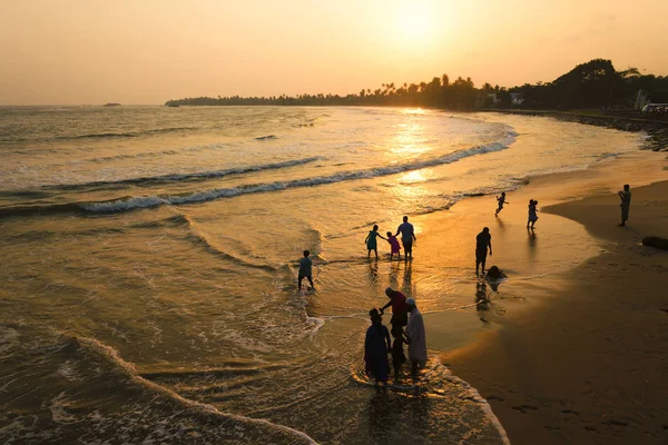 Матара, Шри-Ланка, 04-15-2017: Золотой закат в океане. Силуэт людей, идущих вдоль пляжа и воды. Вид сверху — стоковое фото
