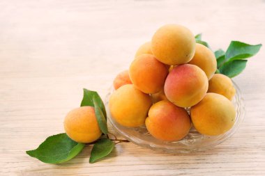 Taze kayısı. Olgun kayısı yapraklarını dökmüş bir cam levha ile. Ahşap arka plan. Üstten Görünüm. Kopya alanı