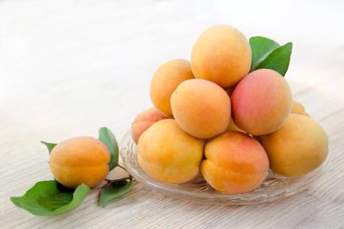 Olgun kayısı. Taze kayısı yaprakları, katlanmış slayt üzerinde bir cam levha ile. Ahşap arka plan. Yan görünümü. Hasat zamanı. Metin için yer