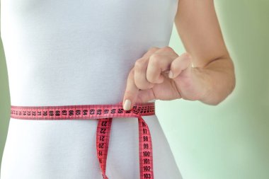 Beyaz sıska mayo bir ince atletik kadında bel ölçüm bandı ile önlemler