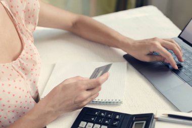 Kadın bir kredi kartı elinde tutan ve bir dizüstü bilgisayarda inşaat ya da satın almalar için öder