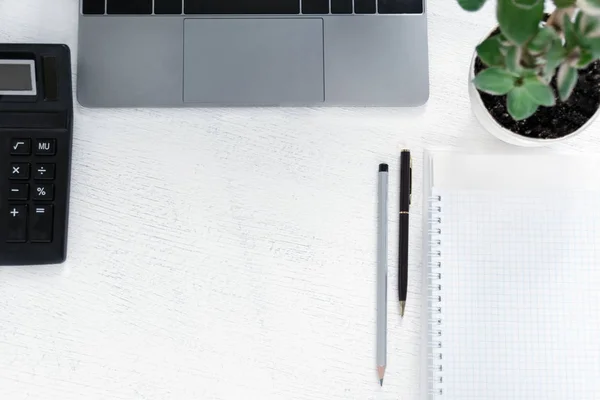 Local de trabalho de negócios com um bloco de notas, uma calculadora, um caderno, uma planta verde. Espaço de cópia — Fotografia de Stock