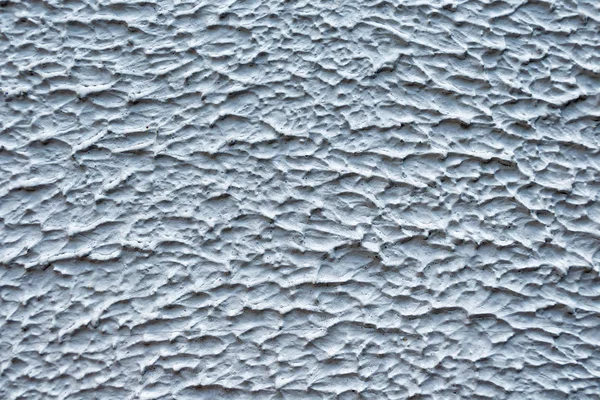 Декоративная штукатурка серо-белого цвета. Гипсовый узор на стене в виде холмистой поверхности . — стоковое фото