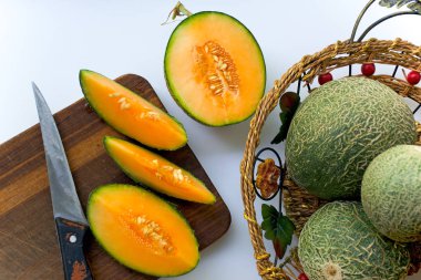 Olgun kavun, yeşil bir kabuk ile sarı içinde tüm ve kesilmiş bir sepet içinde ve bir masada yalan.