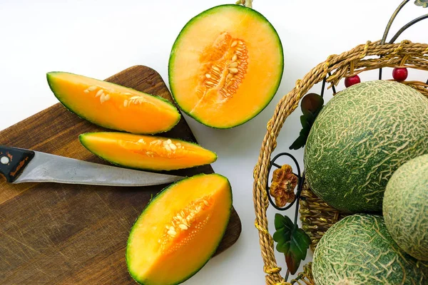Kavun bir yeşil ağaç kabuğu ve bir portakal ortasında ile ürün. Kavun bütün ve kesilmiş yarım.