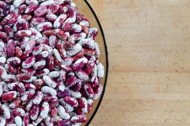 Fasulye çeşitleri Swallow mor, kırmızı ve beyaz noktalı bir ahşap zemin üzerine bir cam plaka. Metin için yer. Üstten Görünüm.