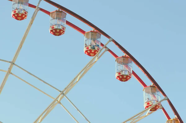An attraction of a Ferris wheel against a blue sky background. The cabin of Ferris wheels closeup.