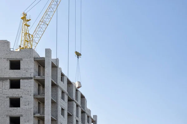 Byggnaden av ett flera våningar tegelhus med hjälp av en konstruktion kran. — Stockfoto