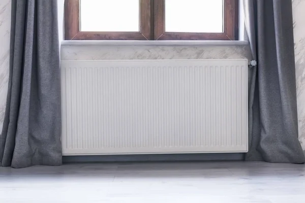 Radiador de aquecimento sob a janela com uma moldura de madeira e cortinas . — Fotografia de Stock