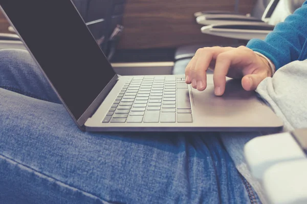 Mano di un giovane in jeans che lavora su un computer portatile in primo piano di trasporto. Foto tonica nello stile di instagram . — Foto Stock