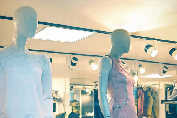 Mannelijke en vrouwelijke mannequins in het venster van een kledingwinkel. Winkeldag. Getinte foto. — Stockfoto