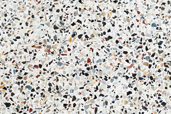 Multi-colored small flat stones on a gray background.