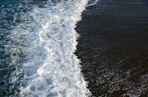 Морская волна с пеной на фоне темного песка. Вид сверху . — стоковое фото