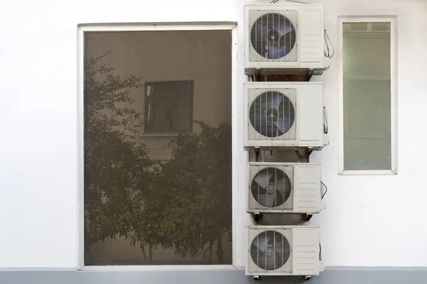 A lot of air conditioners are hanging next to wall near the  window. — Stock Photo, Image