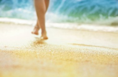Tatil tatil kavramı - deniz kıyısı yürüyen kadın güneş tabaklanmış bacaklarını ayakkabısız silüeti.