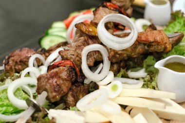 Odak sığ derinliği ile fotoğraf. Sebze, soğan, peynir, salata ve sos ile şiş şiş kebap.