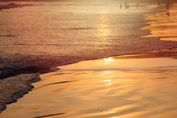 Закат на пляже Фалал в Шри-Ланке - золотой цвет волн морской воды, силуэт людей на заднем плане . — стоковое фото