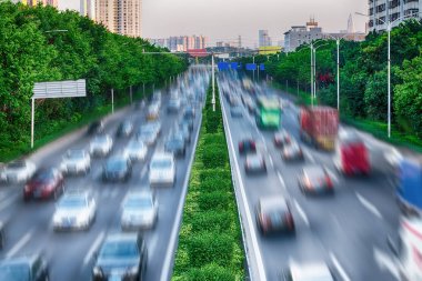 Doğa ve teknoloji - yeşil ağaçlar ve işlek bir yol boyunca yeşil çizgi arasındaki etkileşimi kavramı ortamı korumak. Arabalar meşgul karayolu üzerinde. Benzopyrene, Co2 ve şehirdeki hava kirliliği. Fotoğraf görüntü hareket ile.