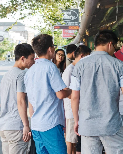 Aziatische vrouw onder de mannen op straat — Stockfoto