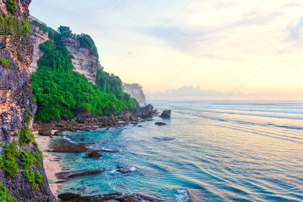 Beach at the foot of the cliff.  Scenic view of a secluded rocky beach before sunset. Bali, Indonesia.