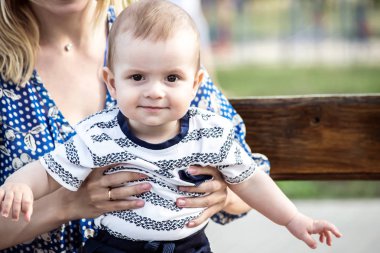 Küçük bebek oğlu bir bankta açık olan genç bir motherr