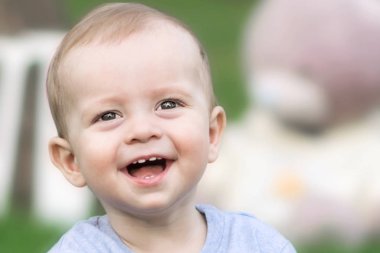 Yakın çekim gülüyor ve kameraya bakarak yaz gün güzel bir bebek çocuk portresi. Arka plan bulanık