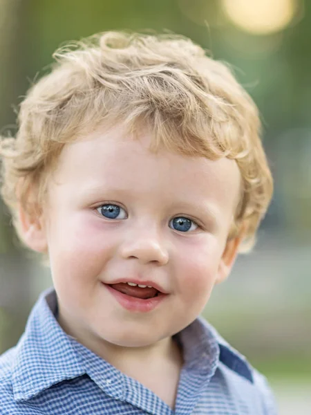 Close-up portret piękny chłopczyk uśmiechając się i patrząc na kamery w letni dzień. Niewyraźne tło — Zdjęcie stockowe