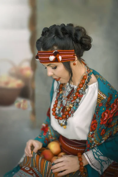 Egy csinos fiatal nő ukrán népviseletben ül és almát tart a kezében. Kozmosz — Stock Fotó