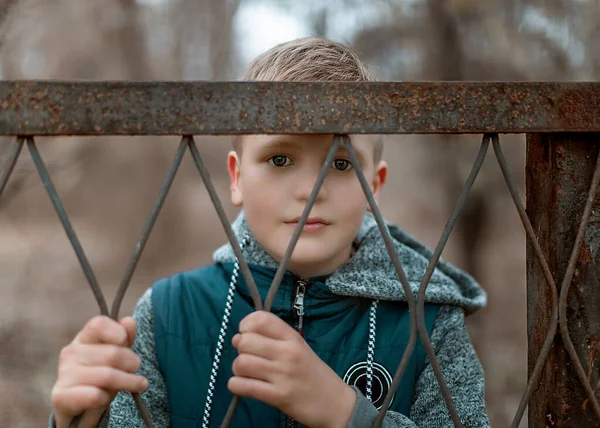 Close-up portret van een schattig tiener jongen staan achter een metalen hek. — Stockfoto