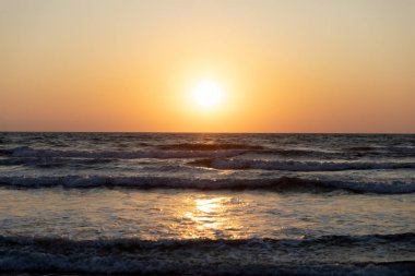 Deniz köpüğü ve spreyli Akdeniz dalgaları. Günbatımı arka planında güzel bir deniz. Gün batımı. Deniz Burnu.