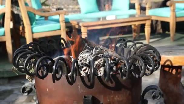 Burning firewood in a decorative heater in a Mediterranean restaurant to warm tourists or guests at cold winter season . Fire in modern metal stove with wood racks. HD video slow motion — Stock Video