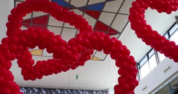 Valentines day decor red balloons in the shape of hearts in shopping mall hanging from the ceiling. Love Day Celebration — Stock Video