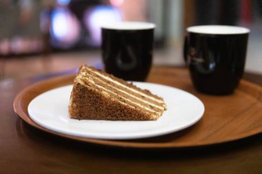 İki kahve fincanı ve bir tabak havuçlu kek ya da akşam veya akşam kafede bir masada yuvarlak bir tepside turta.