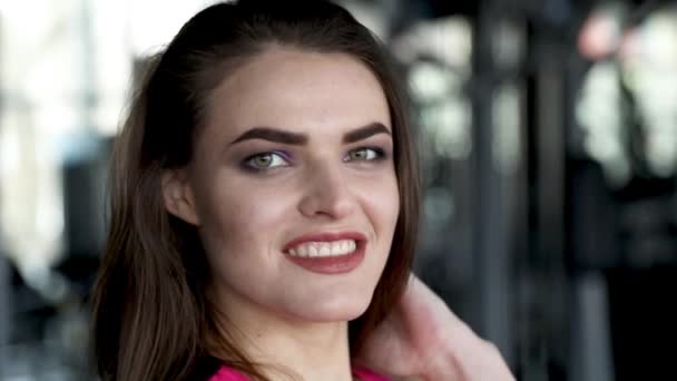 Close-up Retrato de Joven bonita mujer sonriente girando su cara a la cámara en el gimnasio. Estilo de vida pagano, concepción deportiva. Cámara lenta Vídeo Full HD 1920X1080 . — Vídeo de stock