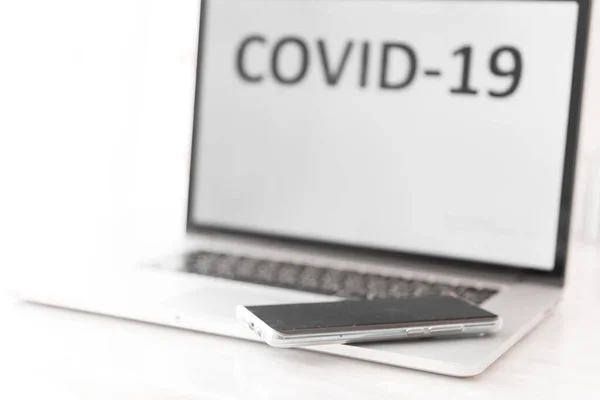 碑文Covid 19とキーボードに横たわるスマートフォンとコンピュータ画面 世界コロナウイルス流行2020 コピースペースの背景 — ストック写真