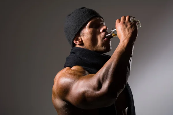 Muscular man drinking alcohol from a bottle — Stock Photo, Image