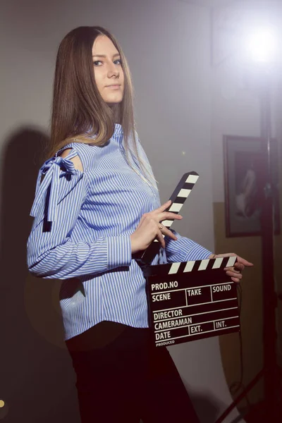 Mujer joven en una camisa a rayas con aplausos de película . —  Fotos de Stock