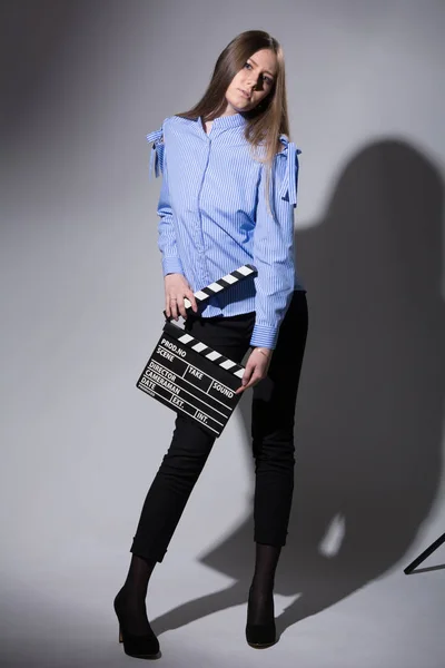 Ung kvinna i en randig tröja med en film kläpp — Stockfoto