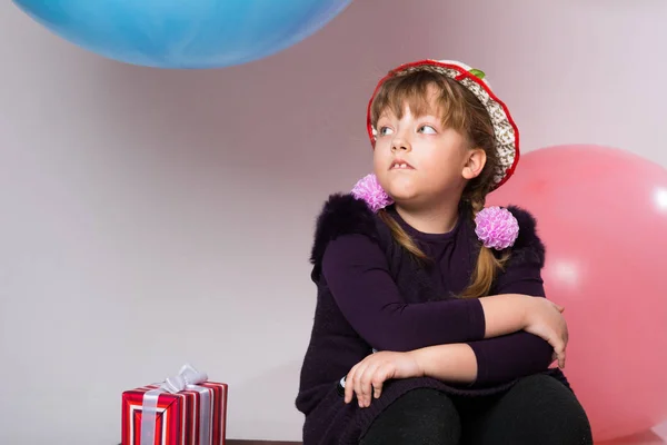 Tankeväckande tonåring i en hatt som sitter med en gåva — Stockfoto