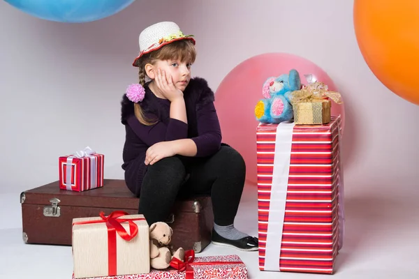 Doordachte tiener in een hoed zittend op een koffer — Stockfoto