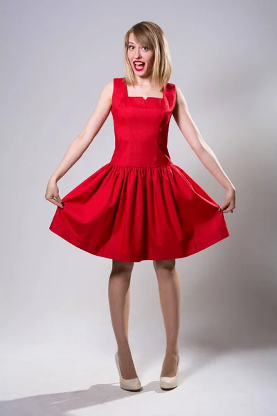 Kırmızı elbise gösterilen süre duran genç gülümseyen kadın — Stok fotoğraf