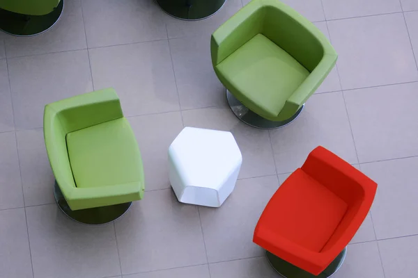 มุมมองด้านบนเก้าอี้สีเขียวสองตัวและสีแดงหนึ่งตัวพร้อมโต๊ะสีขาว — ภาพถ่ายสต็อก