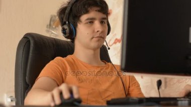 Genç adam kulaklık bilgisayar üzerinde çalışıyor.