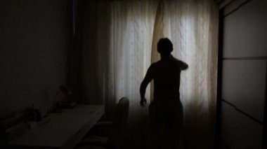 Adam ile bir arka ışık perdeleri bir güneşli sabah açar.