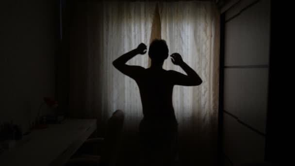 Homem com uma luz de fundo abre as cortinas em uma manhã ensolarada — Vídeo de Stock