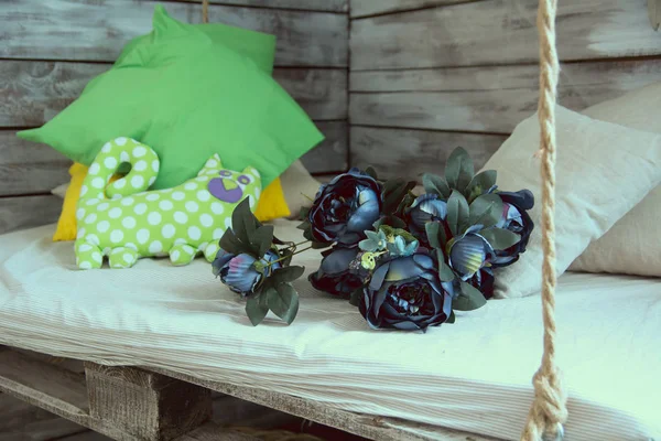 Подвесное сиденье с подушками и букет цветов — стоковое фото