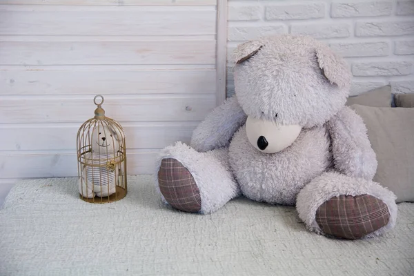 Мишка Тедди сидит на кровати рядом с маленьким медвежонком в клетке — стоковое фото